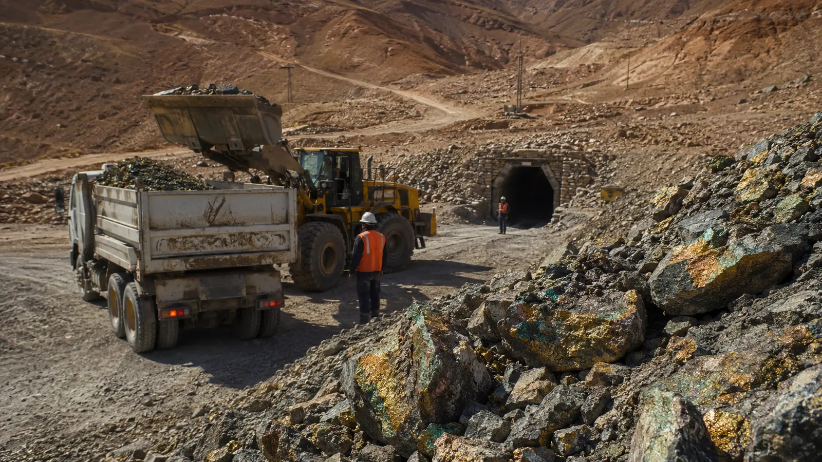 Copper sulphide ore being loaded into haul trucks beside a small underground mine portal in northern Chile